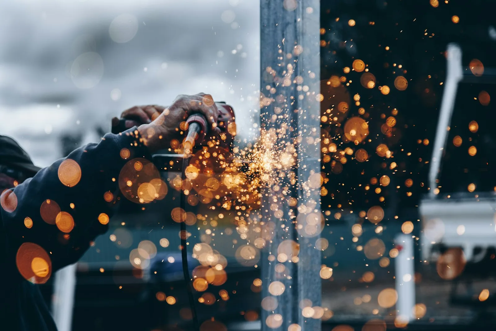 Sparks flying from a worker grinding metal in an industrial workshop