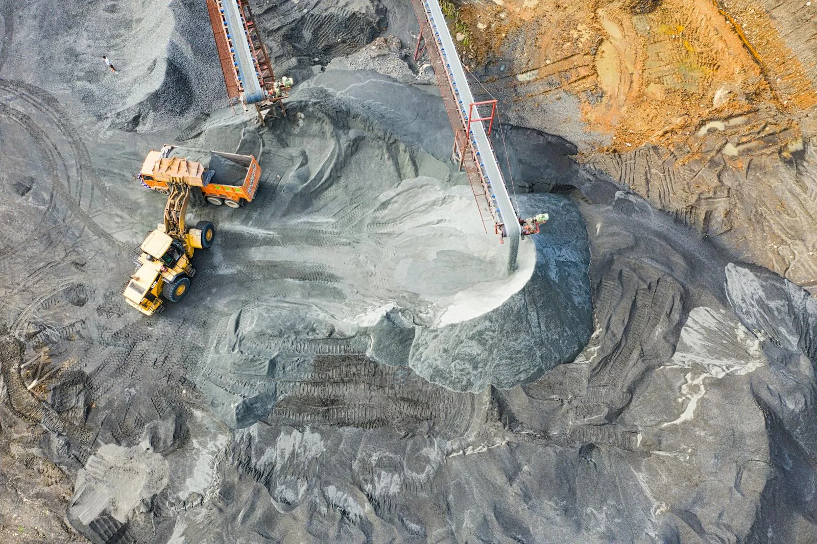 Aerial view of a haul truck and conveyor at an open-pit mine